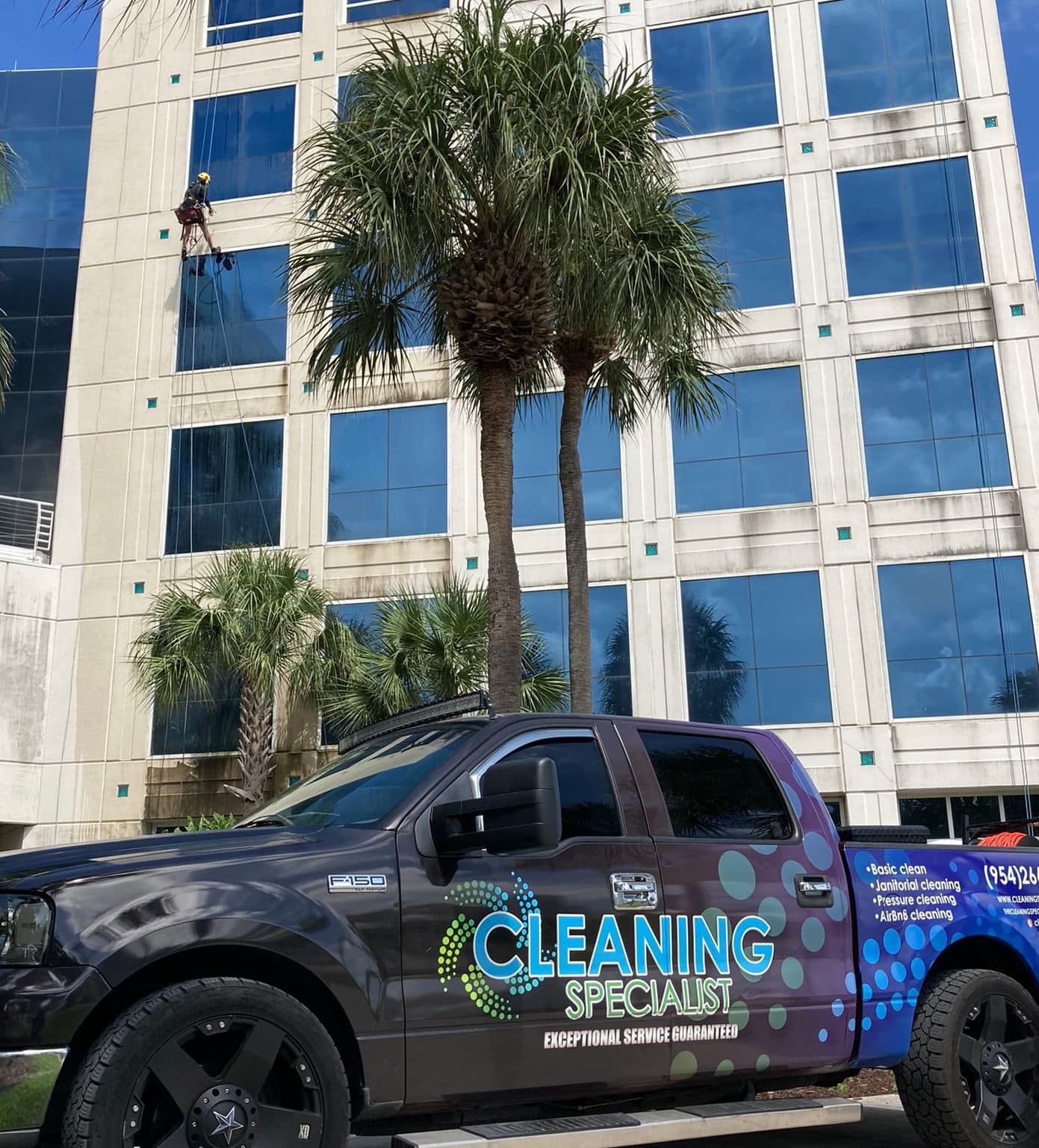 Camión de Cleaning Specialist USA y técnico de acceso por cuerda en un edificio alto